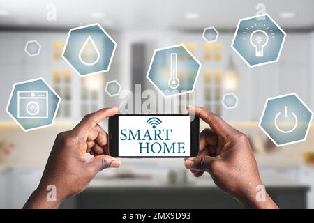 Ein Mann, der eine Telefonanwendung zur Steuerung von Smart-Home in Innenräumen verwendet, Nahaufnahme Stockfoto