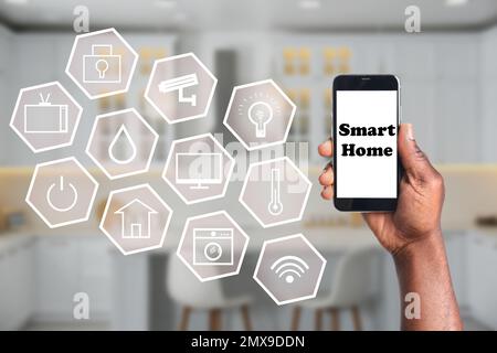 Ein Mann, der eine Telefonanwendung zur Steuerung von Smart-Home in Innenräumen verwendet, Nahaufnahme Stockfoto