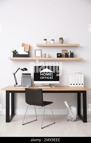 Moderner Computer mit Text HOME OFFICE auf weißem Holz im Innenbereich Stockfoto