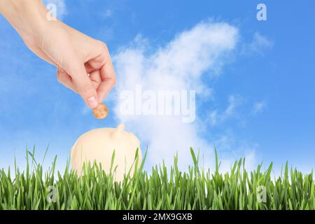 Eine Frau, die draußen Geld in die Sparschweinbank steckt, macht dicht. Platz für Text Stockfoto