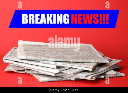 Phrase Breaking News und Zeitungsstapel auf rotem Hintergrund. Journalistenarbeit Stockfoto