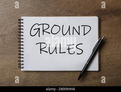 Notizbuch mit Text GRUNDREGELN und Stift auf Holztisch, Draufsicht Stockfoto