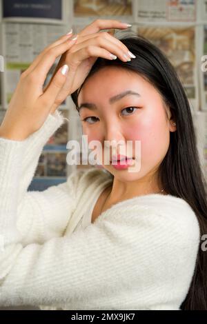 Nahaufnahme eines wunderschönen asiatischen Mädchens mit Händen, die das Gesicht umrahmen Stockfoto