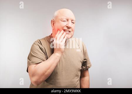 Älterer Mann mit Zahnschmerzen auf grauem Hintergrund Stockfoto