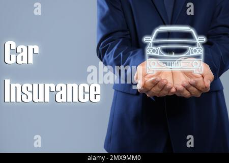 Ein Mann, der ein Bild von Auto auf grauem Hintergrund vorführt, Nahaufnahme. Autoversicherung Stockfoto