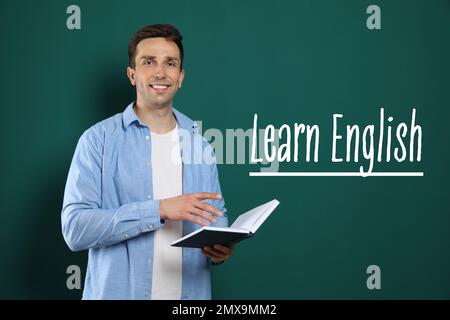 Junger Englischlehrer mit Buch in der Nähe der Tafel Stockfoto