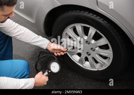 Mechaniker, der den Reifendruck im Autorad an der Tankstelle überprüft, Schließung Stockfoto