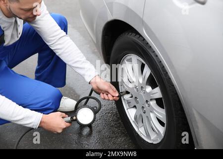 Mechaniker, der den Reifendruck im Autorad an der Tankstelle überprüft, Schließung Stockfoto