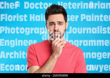 Verwirrter junger Mann, der seinen Beruf auf blauem Hintergrund wählt Stockfoto