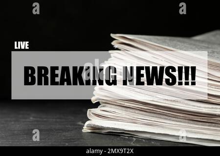 Phrase Breaking News und ein Stapel Zeitungen auf dem Tisch. Journalistenarbeit Stockfoto