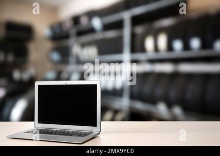 Moderner Laptop auf dem Tisch im Autoladen. Platz für Text Stockfoto