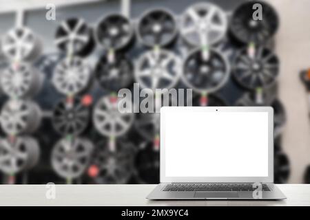 Moderner Laptop auf dem Tisch im Autoladen. Platz für Text Stockfoto