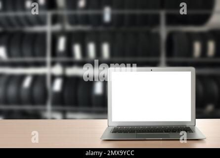 Moderner Laptop auf dem Tisch im Autoladen. Platz für Text Stockfoto