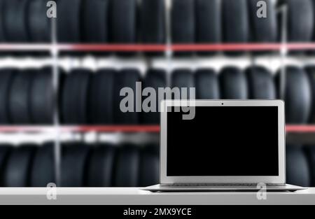 Moderner Laptop auf dem Tisch im Autoladen. Platz für Text Stockfoto