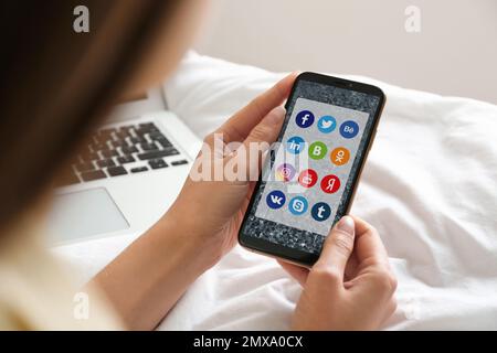 MYKOLAIV, UKRAINE - 30. APRIL 2020: Frau mit Telefon und Social-Media-Apps-Symbolen auf dem Bildschirm in Innenräumen, Nahaufnahme Stockfoto