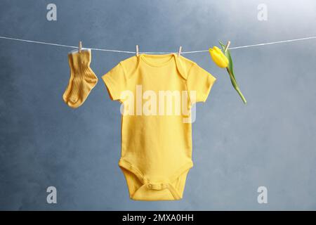 Kinderanzug, Paar Socken und Blume, die vor dunklem Hintergrund an der Wäscheleine hängen Stockfoto