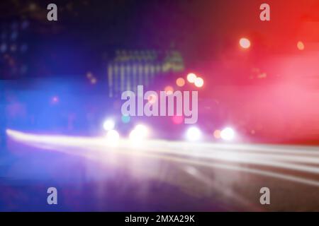 Verschwommener Blick auf Polizeiautos auf der Straße bei Nacht Stockfoto