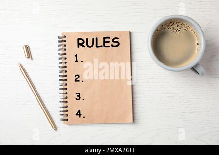 Notizbuch mit Regelliste und Tasse Kaffee auf Holzhintergrund, flach liegend Stockfoto