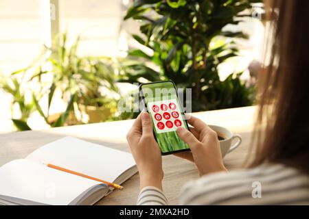 MYKOLAIV, UKRAINE - 30. APRIL 2020: Frau mit Telefon und Social-Media-Apps-Symbolen auf dem Bildschirm in Innenräumen, Nahaufnahme Stockfoto