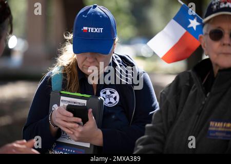 Austin Texas, USA, Januar 29 2023: Eine Frau mit „Texit“-Mütze und Jacke mit dem Logo der texanischen Nationalbewegung überprüft ihr Handy, während sie bei einer leicht besuchten Rallye im Texas Capitol teilnimmt. Die kleine Gruppe drängte die Gesetzgeber, Pläne zu machen, damit sich die Statea von den Vereinigten Staaten abspaltet. ©Bob Daemmrich Stockfoto