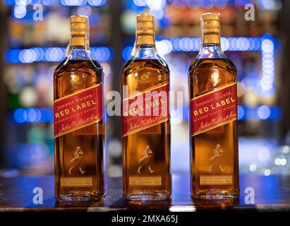 LEMBERG, UKRAINE - 3. SEPTEMBER 2022: johnnie Walker rotes Etikett drei Glasflaschen auf der Theke mit wunderschönem Bokeh und Licht im Hintergrund Stockfoto