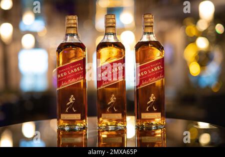 LEMBERG, UKRAINE - 3. SEPTEMBER 2022: johnnie Walker rotes Etikett drei Glasflaschen auf der Theke mit wunderschönem Bokeh und Licht im Hintergrund Stockfoto