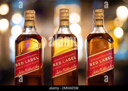 LEMBERG, UKRAINE - 3. SEPTEMBER 2022: johnnie Walker rotes Etikett drei Glasflaschen auf der Theke mit wunderschönem Bokeh und Licht im Hintergrund Stockfoto