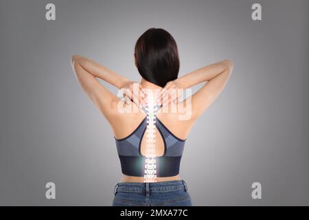 Frau mit Wirbelsäulenschmerzen auf grauem Hintergrund Stockfoto