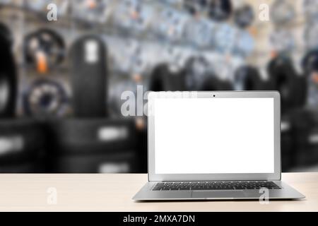 Moderner Laptop auf dem Tisch im Autoladen. Platz für Text Stockfoto