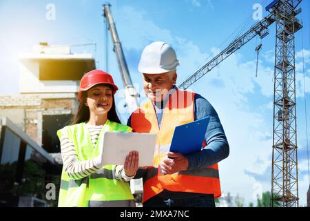 Professioneller Ingenieur und Vorarbeiter in der Sicherheitsausrüstung mit Tablet auf der Baustelle Stockfoto