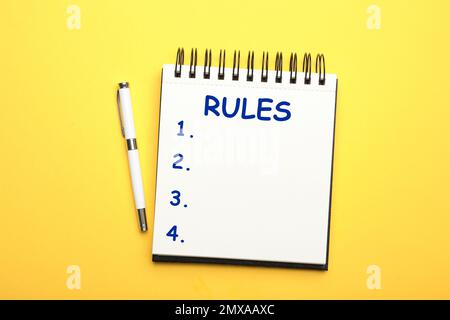 Notizbuch mit Regelliste und Stift auf gelbem Hintergrund, flach liegend Stockfoto
