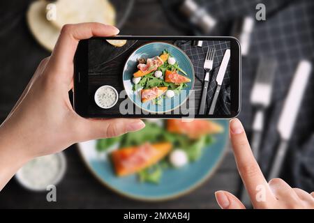 Blogger macht ein Foto von frischer Melone mit Prosciutto am Tisch, Nahaufnahme. Lebensmittelfotografie Stockfoto