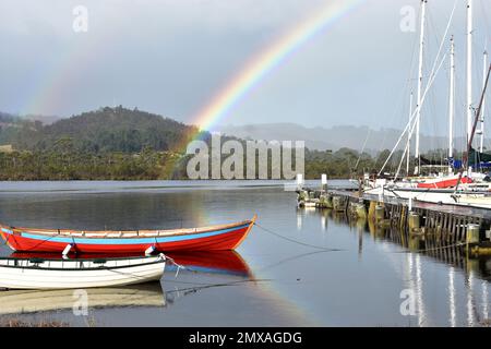 Pier mit Regenbogen und Yachten in der Nähe des Wooden Boat Centre in Franklin, Cygnet, Tasmanien. Stockfoto