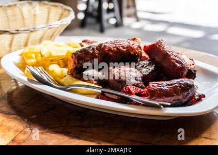 Auf Gran Canaria, Spanien, werden Wurst-, Kalb- und Schweinefleisch gegrillt und mit pommes frites serviert Stockfoto