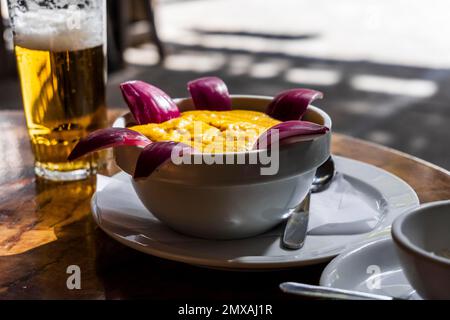 Köstliche traditionelle Speisen von Gran Canaria namens Gofio Escaldado werden mit rohen roten Zwiebeln gegessen Stockfoto