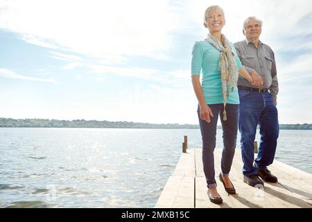 Spaziergang entlang des Piers. Ein vollständiges Bild eines erwachsenen Paares, das auf einem Steg läuft. Stockfoto