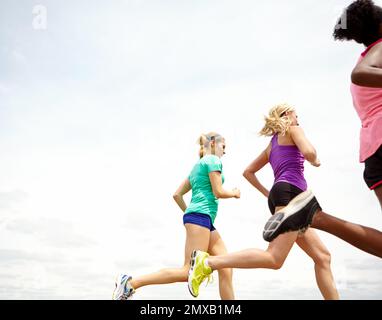 Fit in Frischluftumgebungen. Freigestellte Seitenansicht einer Gruppe von Sportlern, die im Freien joggen. Stockfoto
