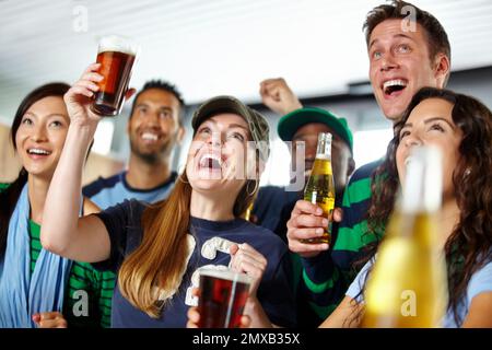 Sehen, wie ihre Lieblingsmannschaft gewinnt. Eine Gruppe von aufgeregten Freunden, die ihr Lieblingsteam an der Bar anfeuern. Stockfoto