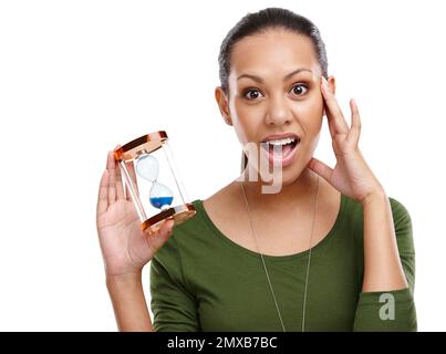 Wo das Jahr vergangen ist. Porträt einer schockierten jungen Frau, die eine Sanduhr auf Weiß hält. Stockfoto