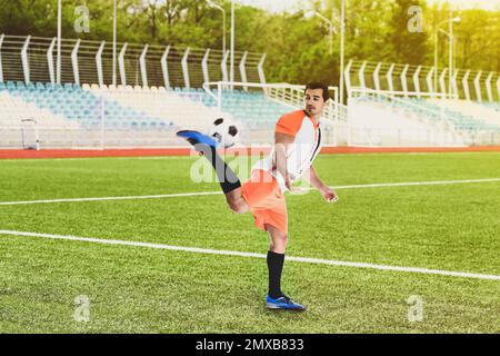 Junger Mann in Uniform, der im Stadion Football spielt Stockfoto