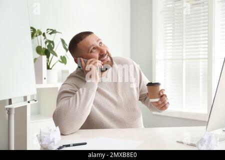 Fauler, übergewichtiger Büroangestellter, der am Arbeitsplatz telefoniert Stockfoto