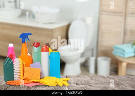 Verschiedene Reinigungsmittel auf Holztisch im Bad, Platz für Text Stockfoto