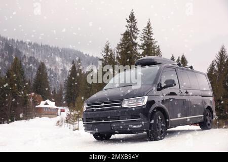 Schwarzes Auto auf verschneiter Straße. Winterurlaub Stockfoto