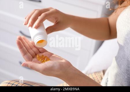 Afroamerikanerin mit einer Flasche Vitaminkapseln zu Hause, Nahaufnahme Stockfoto