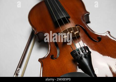 Schöne Geige und Schleife auf grauem Steintisch, Nahaufnahme Stockfoto