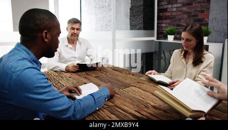 Junge, Multiethnische Menschen, Die Über Dem Holzschreibtisch Bibel Lesen Stockfoto