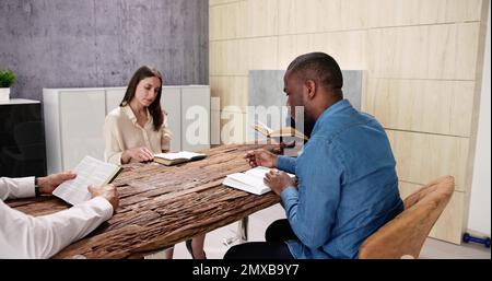Junge, Multiethnische Menschen, Die Über Dem Holzschreibtisch Bibel Lesen Stockfoto