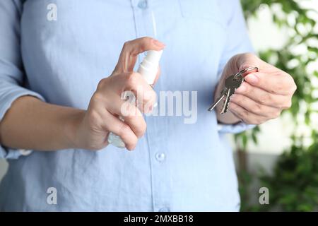 Eine Frau, die in geschlossenen Räumen Antiseptikum auf Schlüssel spritzt, Nahaufnahme Stockfoto