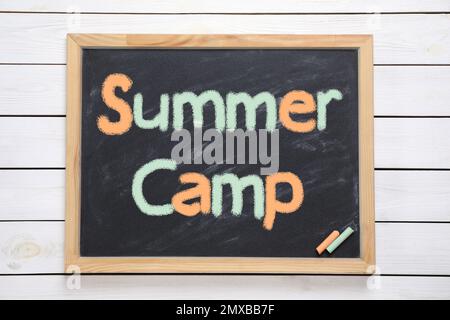 Tafel mit Text SOMMERCAMP auf weißem Holzhintergrund, Draufsicht Stockfoto