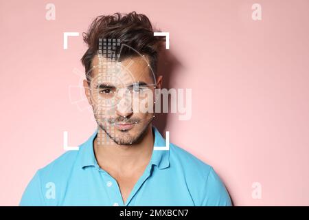 Gesichtserkennungssystem. Junger Mann mit Scannerrahmen und digitalem biometrischem Raster auf pinkem Hintergrund Stockfoto